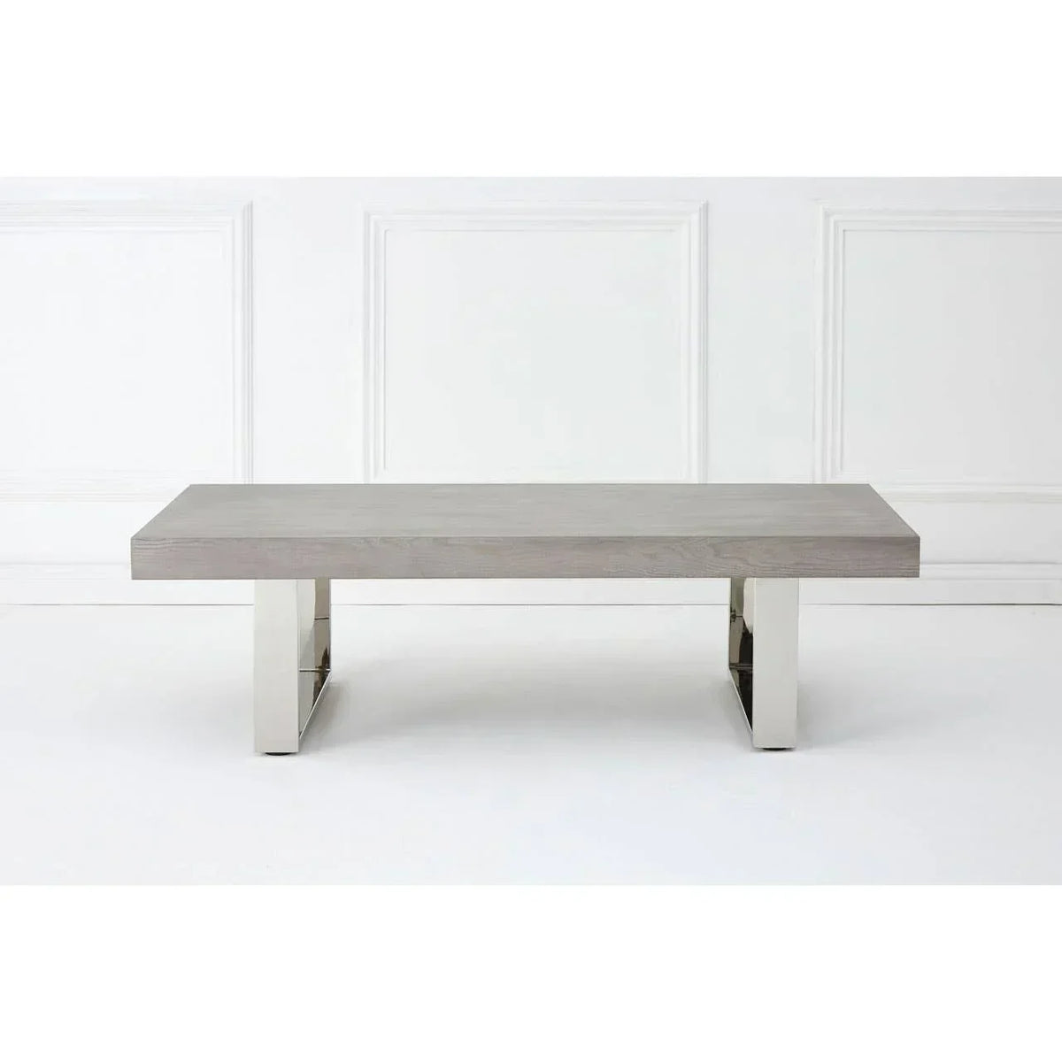 Modern coffee table with grey wood top and chrome legs against white wall panel background
