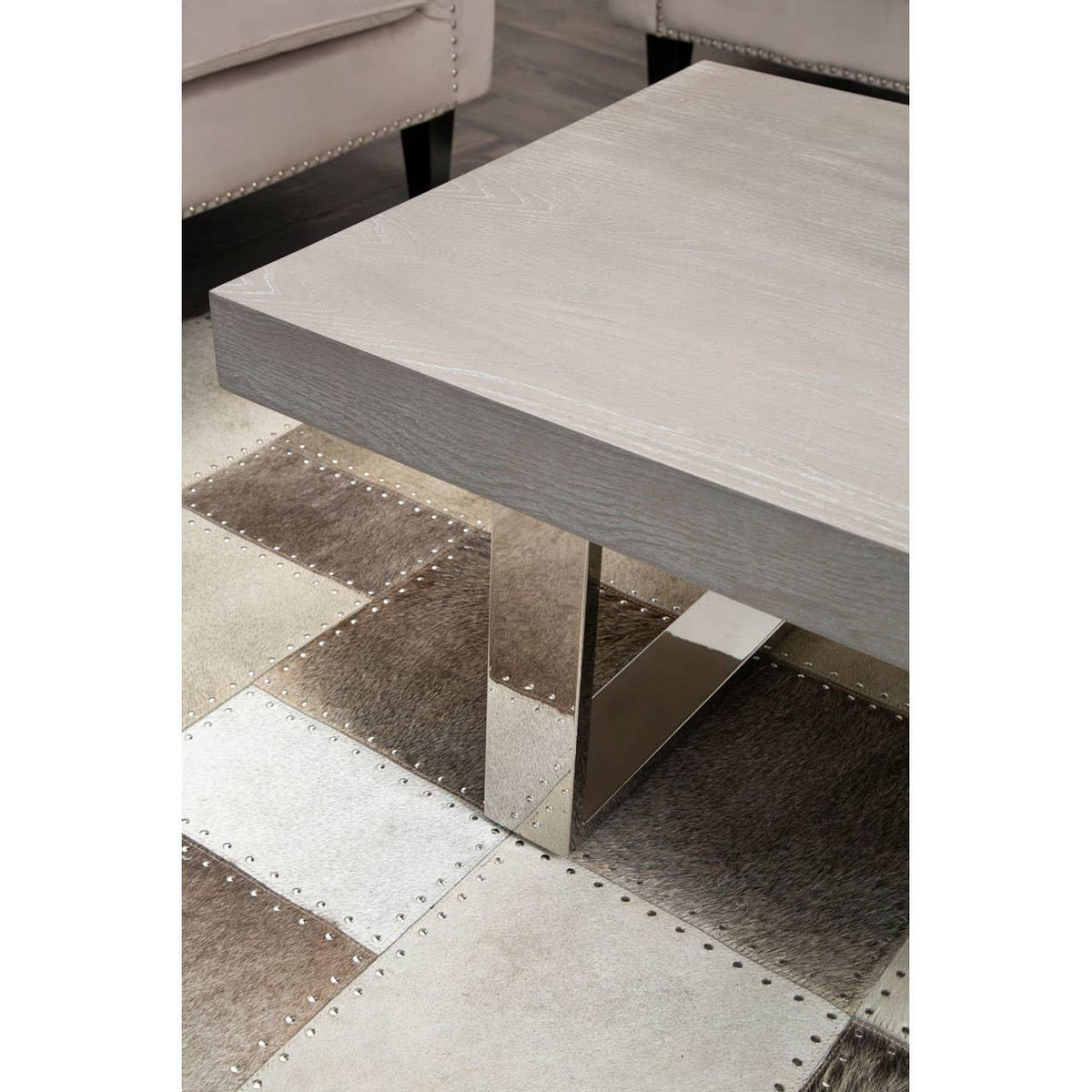 Modern square coffee table with light wood top and chrome legs on patchwork rug