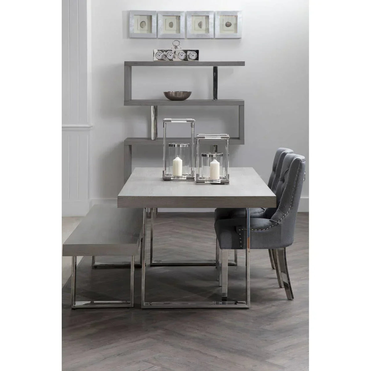 Modern grey dining table set with bench, upholstered chairs, and chrome accents in a bright room