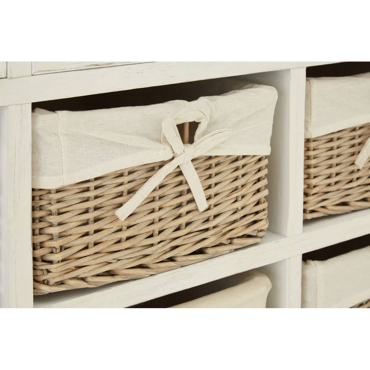 A close-up view of a willow basket from the Hendra Storage Cabinet, featuring a natural woven design with a cream-colored fabric lining and a decorative bow on the front. The cabinet has multiple compartments, showcasing the basket's texture and craftsmanship