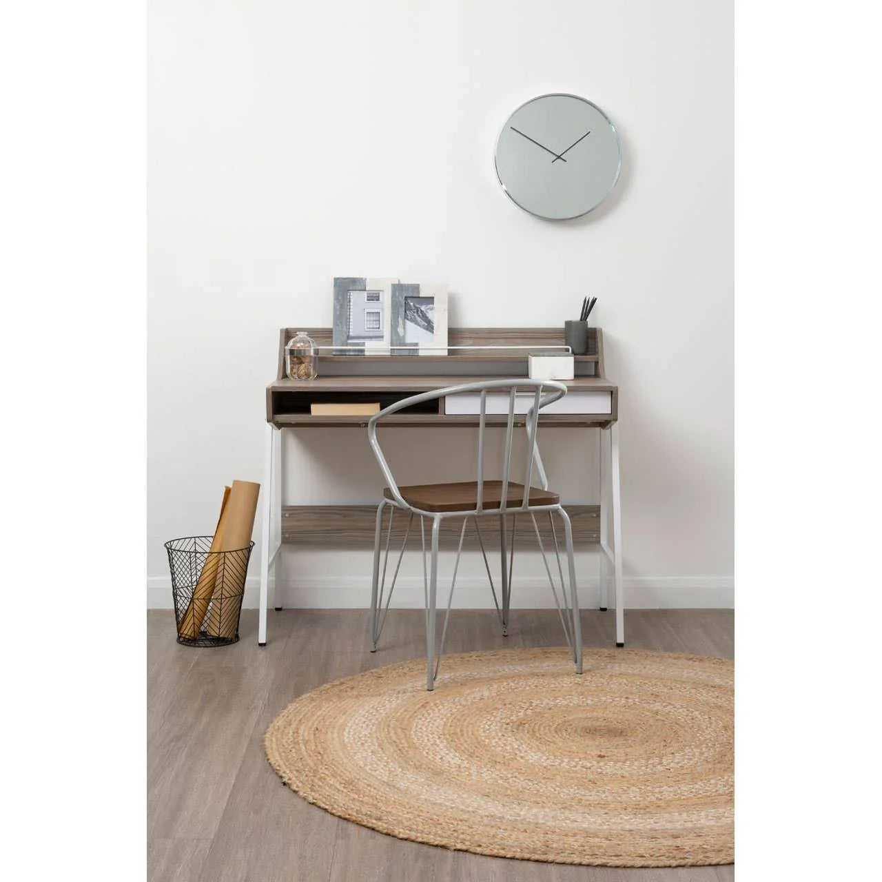 Wood and metal home office desk with modern chair, round jute rug, and wall clock