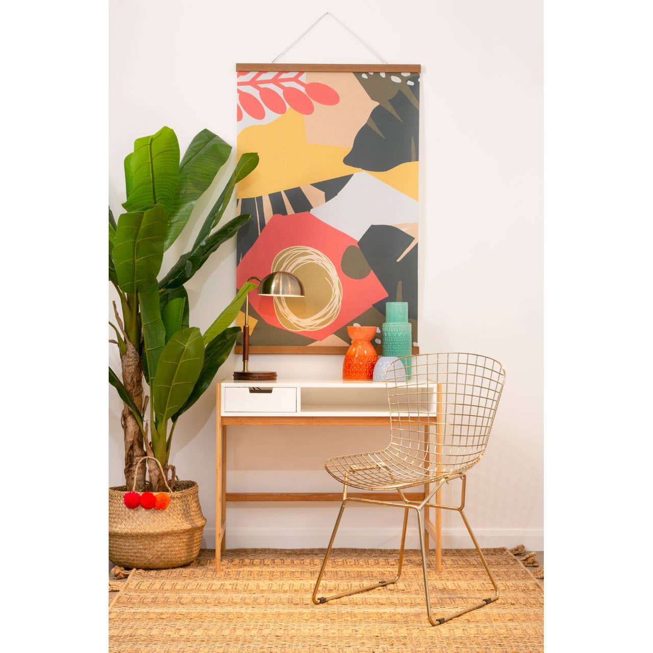Gold metal grid frame wire chair positioned next to a small desk with a decorative vase and a plant. The wall features a colorful abstract art piece, adding a vibrant touch to the scene. The floor is wooden, enhancing the warm aesthetic of the space