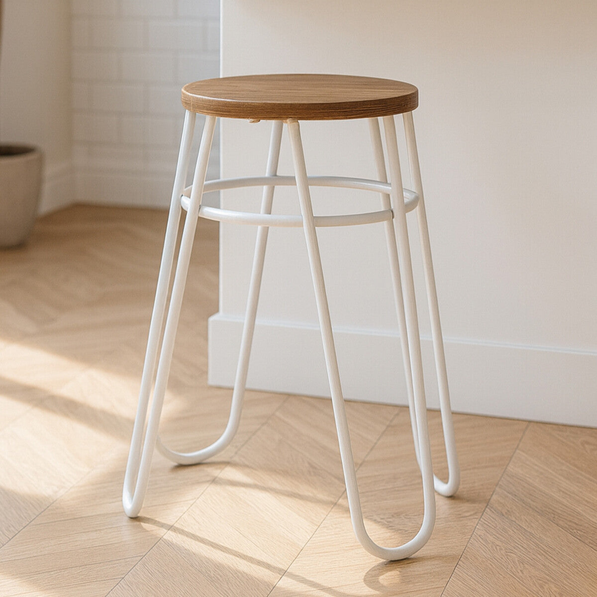 A grey metal hairpin stool with a round wooden seat, featuring slender, curved legs and a minimalist design, placed on a light wooden floor
