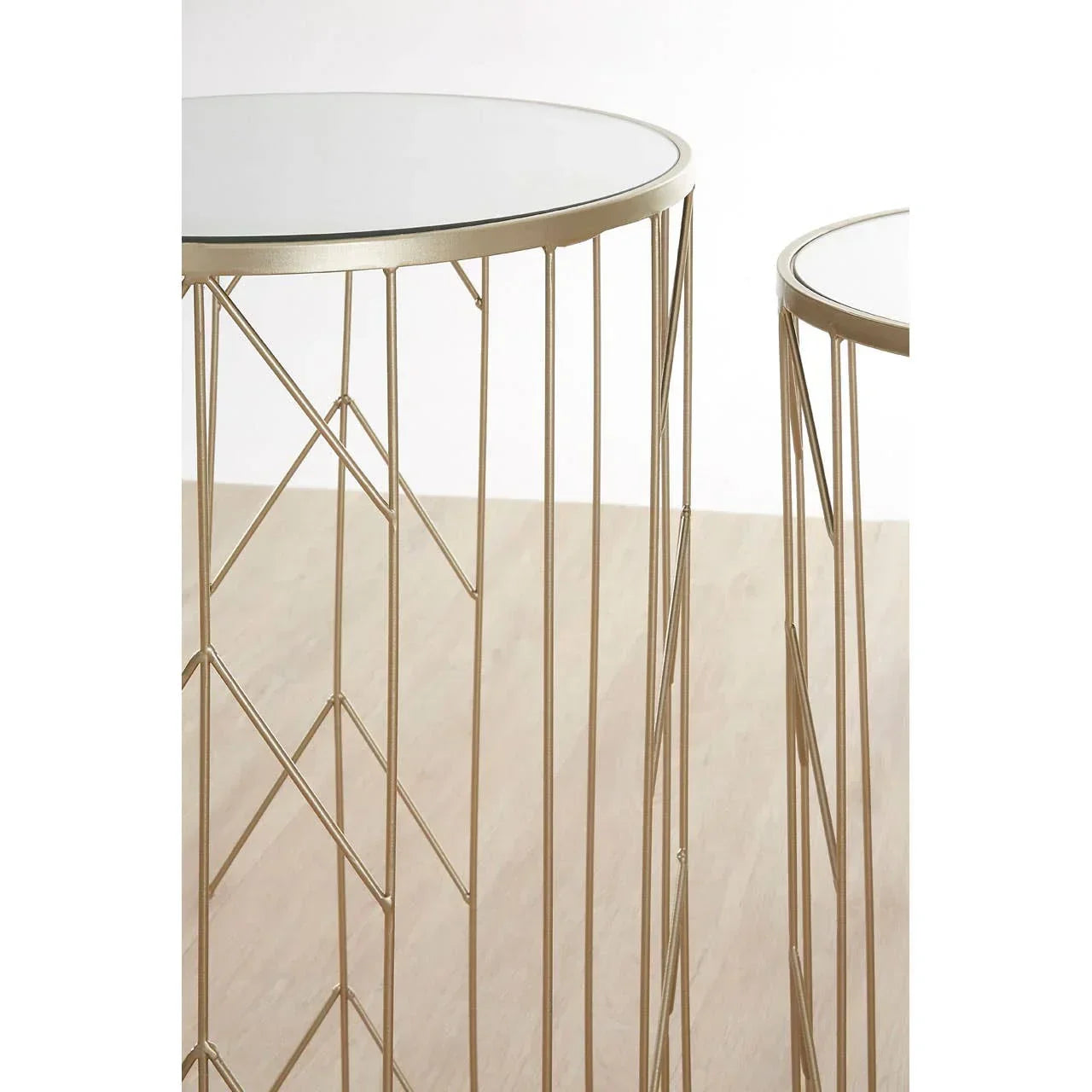 Round nesting side tables with gold metal frame and mirrored top on wooden floor