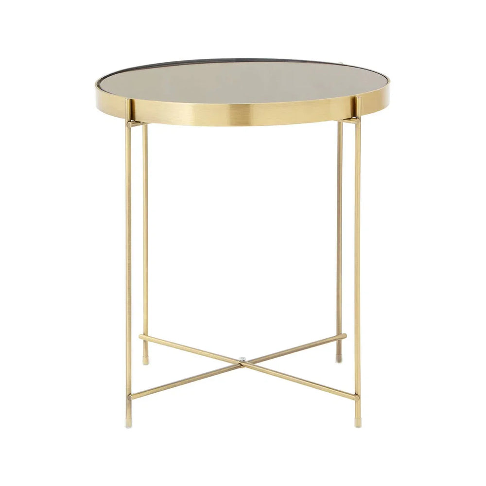 Round glass top side table with gold metal frame and crossed legs on white background