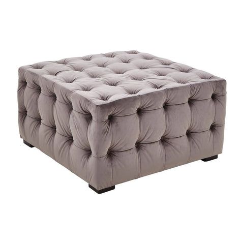 Square stool upholstered in soft grey velvet, featuring a button-tufted design with deep indentations and a smooth surface. The stool has rounded corners and rests on four small, dark legs