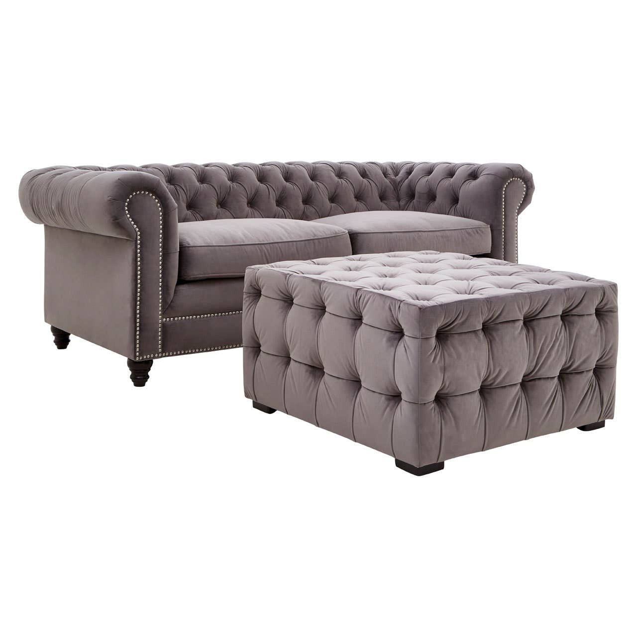 Grey velvet stool featuring button tufting and a square shape, with rounded edges and short wooden legs. The fabric has a soft, luxurious appearance, complementing a stylish home decor
