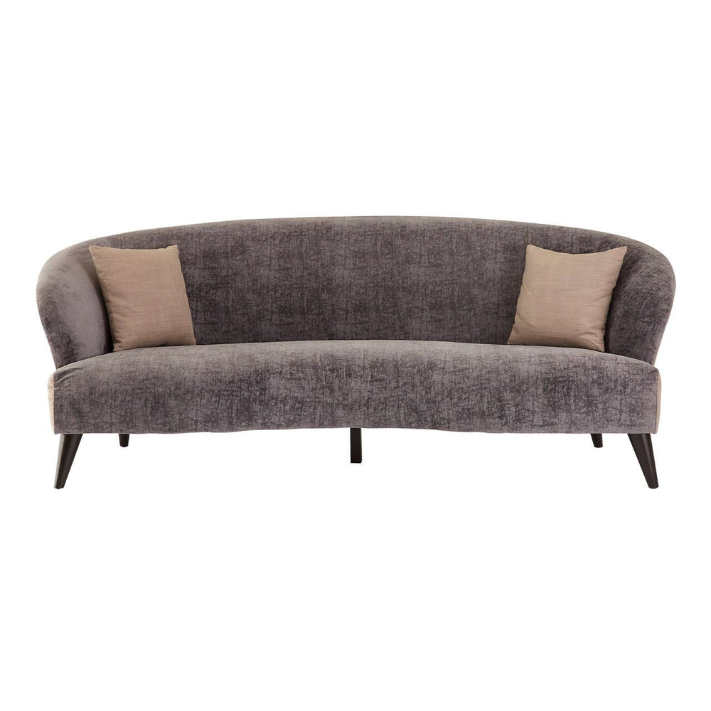 Three-seat sofa upholstered in grey velvet with a curved backrest and two contrasting beige throw pillows. The sofa features sleek wooden legs and a modern design, suitable for contemporary living spaces