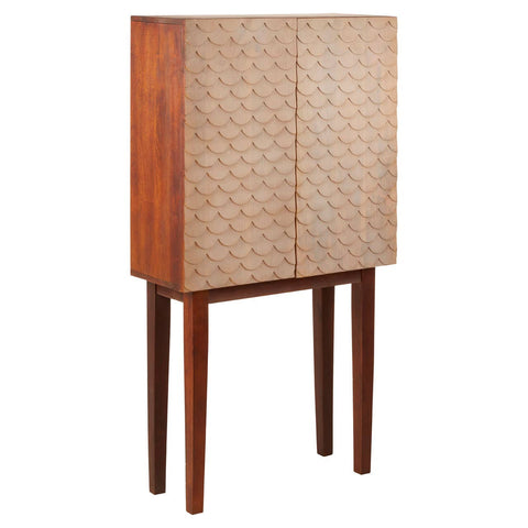A tall cabinet made from mango wood featuring a warm brown finish, with two textured doors displaying a geometric pattern. The cabinet stands on four slender legs, adding a modern touch to its coastal design