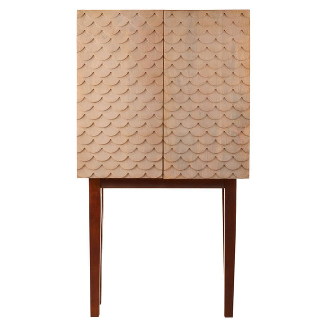 A coastal carved mango wood cabinet featuring a textured front with geometric patterns, two doors, and slender wooden legs. The cabinet has a natural wood finish that highlights the grain and craftsmanship