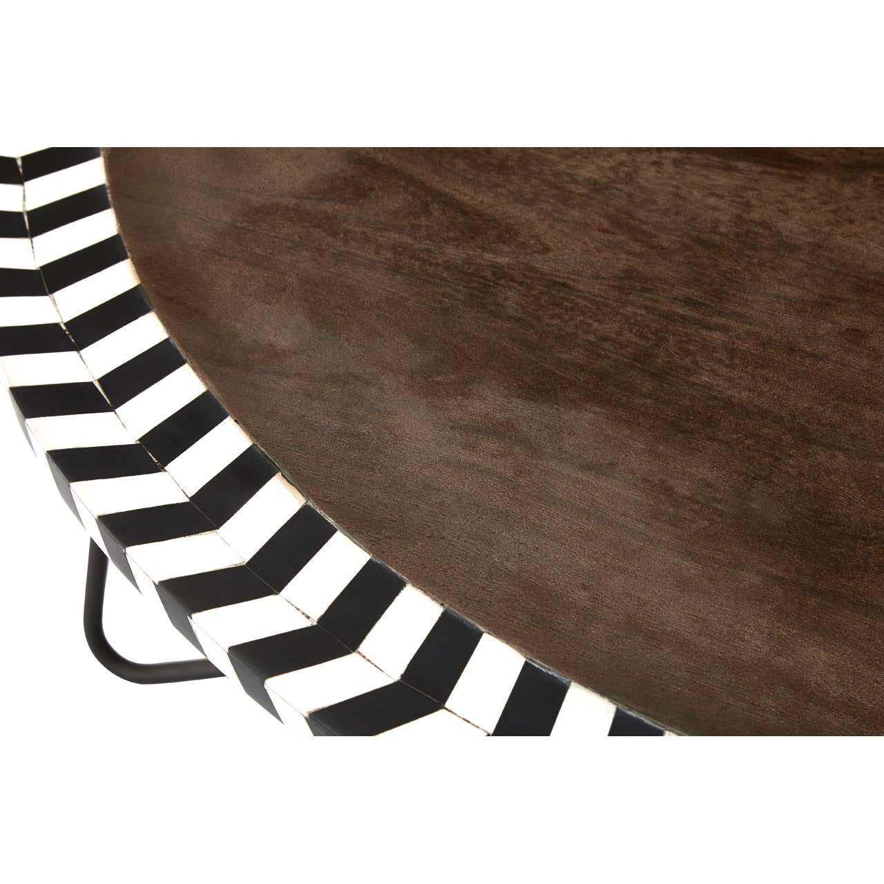 Round wooden table with black and white chevron edge detail, close up of tabletop