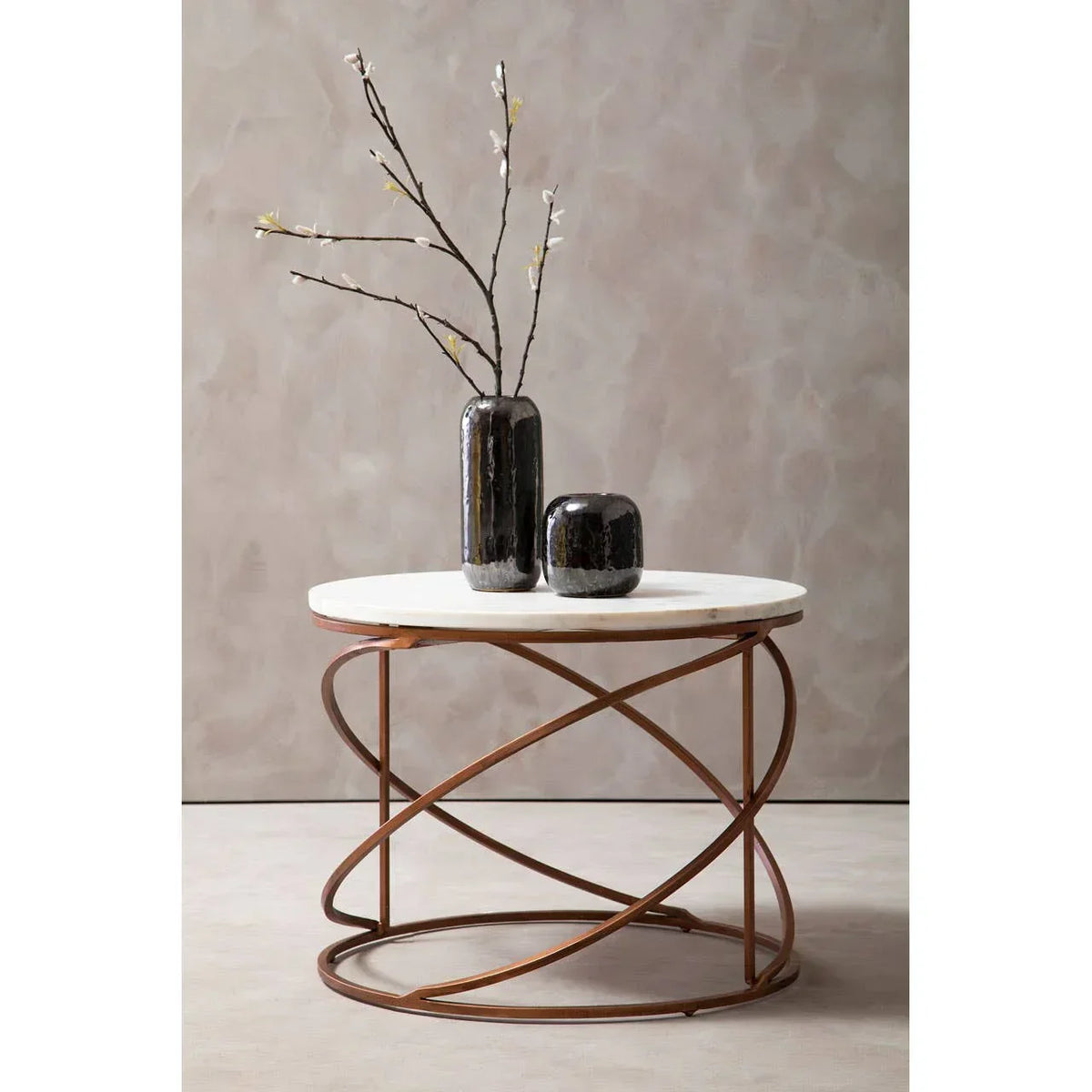 Round marble top coffee table with bronze geometric metal base, two black vases on top