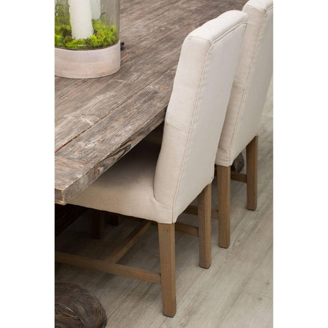 Rustic wooden dining table with beige upholstered dining chairs on wood floor