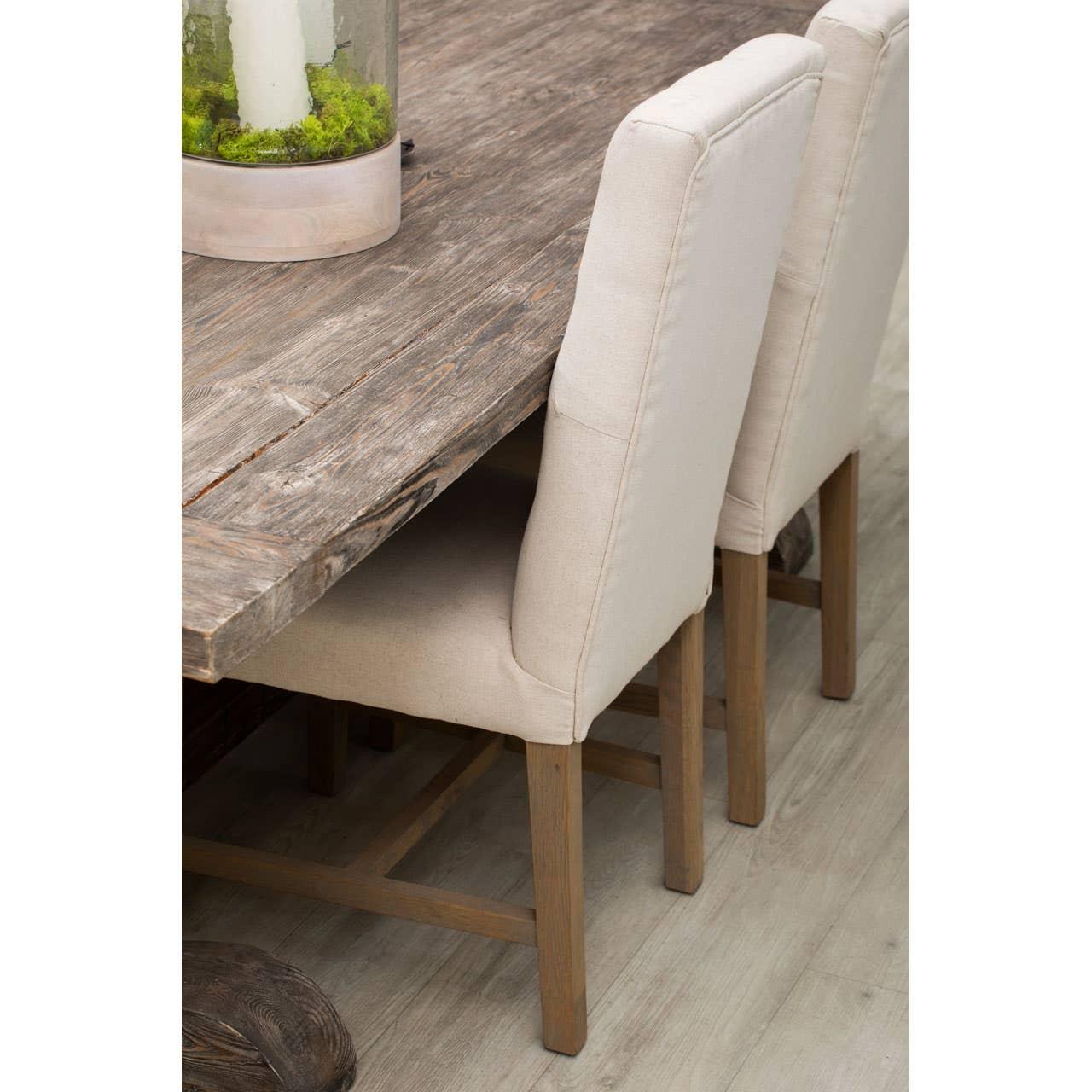 Rustic wooden dining table with beige upholstered dining chairs on wood floor