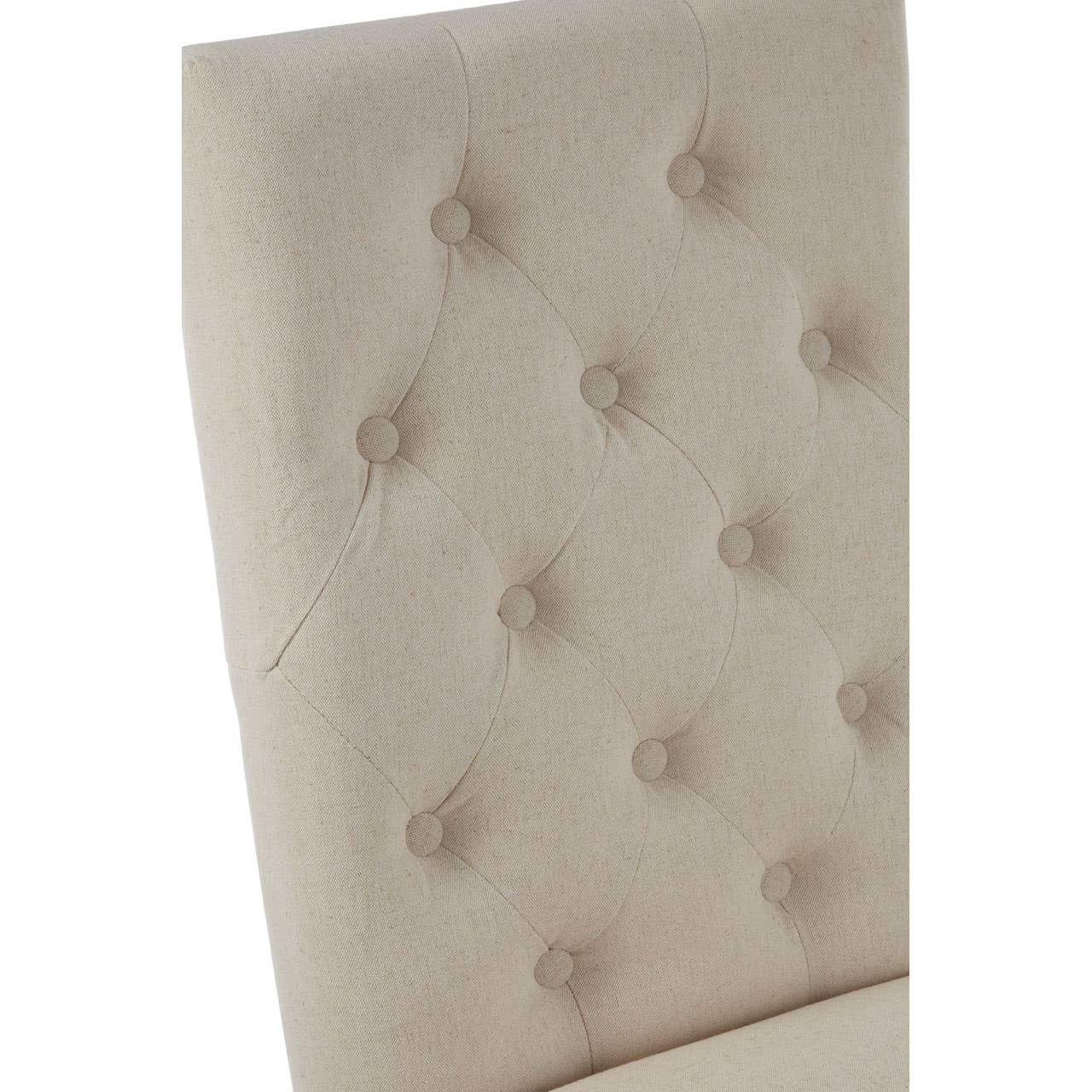 Beige fabric dining chair with button-tufted backrest, close-up angle