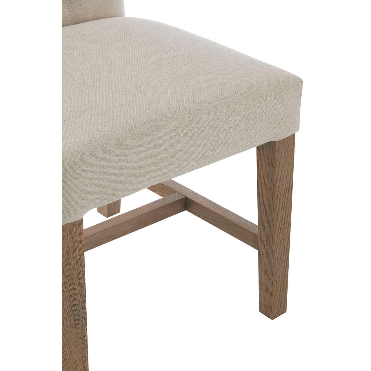 Beige upholstered dining chair seat with oak wooden legs, side angle view