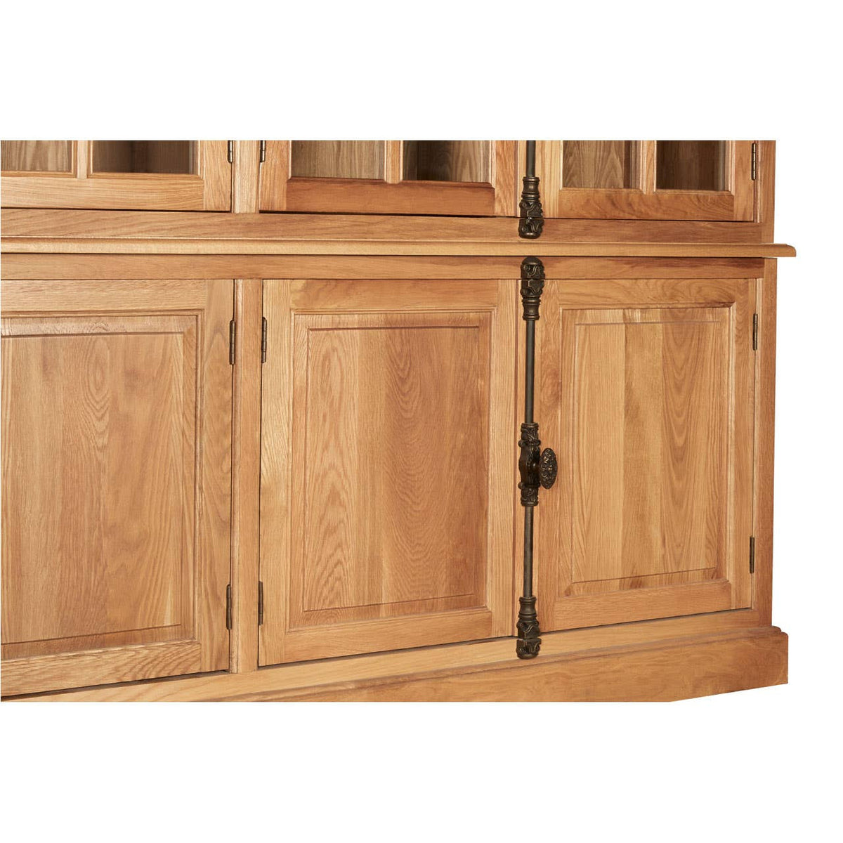 Large cabinet made of natural oak wood featuring multiple doors with a smooth finish and black metal hardware. The cabinet has a warm, light wood tone and showcases a classic design with a curved base