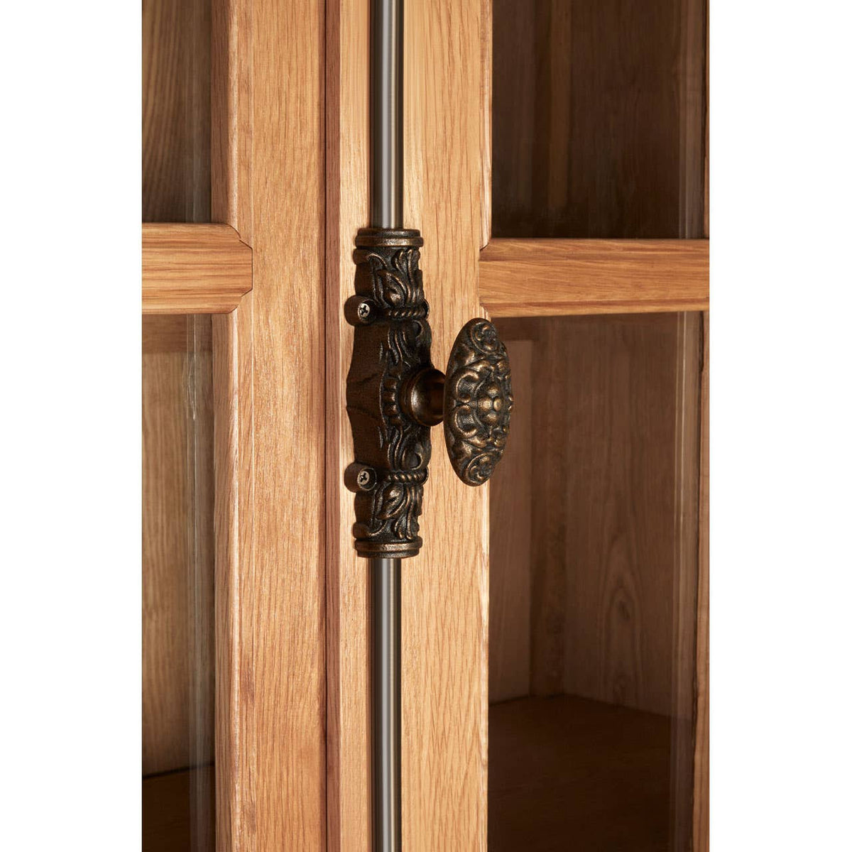 Close-up view of the Lyon Natural Oak Wood Large Cabinet featuring a decorative metal handle and glass doors, showcasing the warm tones and natural grain of the oak wood