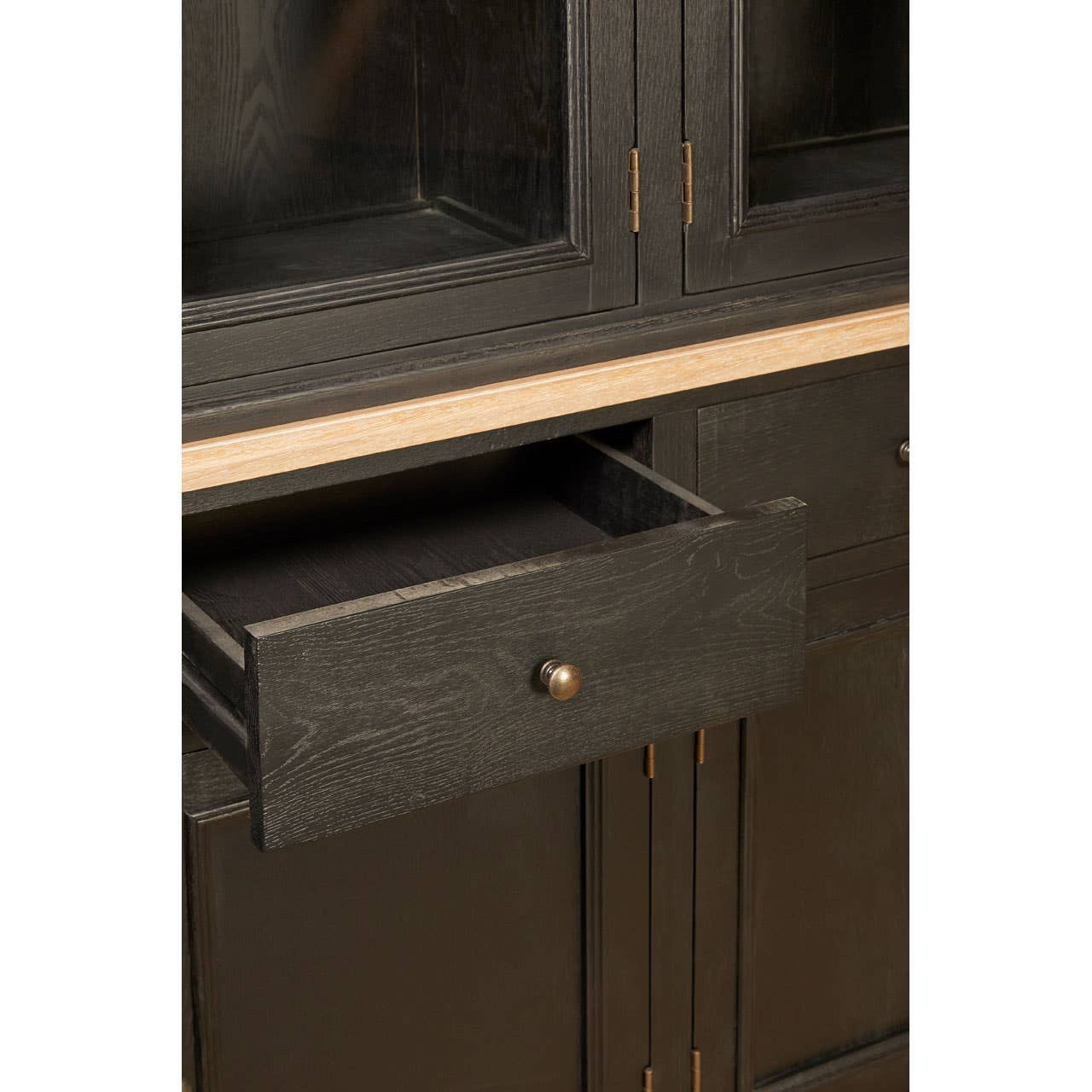 Close-up view of a black oak wood cabinet featuring a single drawer with a round handle, showcasing a sleek design and a smooth finish. The cabinet has a minimalist aesthetic with clean lines and a natural wood grain texture
