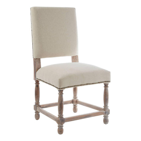 Beige upholstered dining chair with wooden legs and nailhead trim on white background