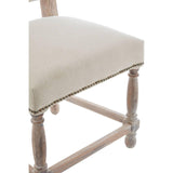 Beige upholstered dining chair seat with wooden legs and brass stud trim