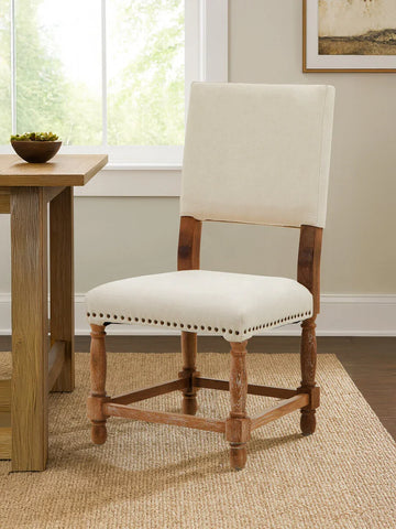 Beige upholstered dining chair with wooden legs beside oak dining table in modern room