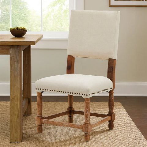 Cream upholstered dining chair with wooden legs beside oak dining table