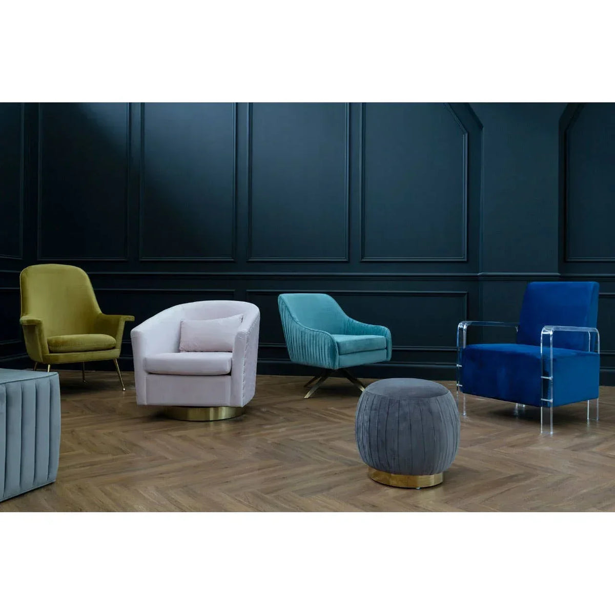 Velvet accent chairs and footstool in assorted colors on herringbone wood floor