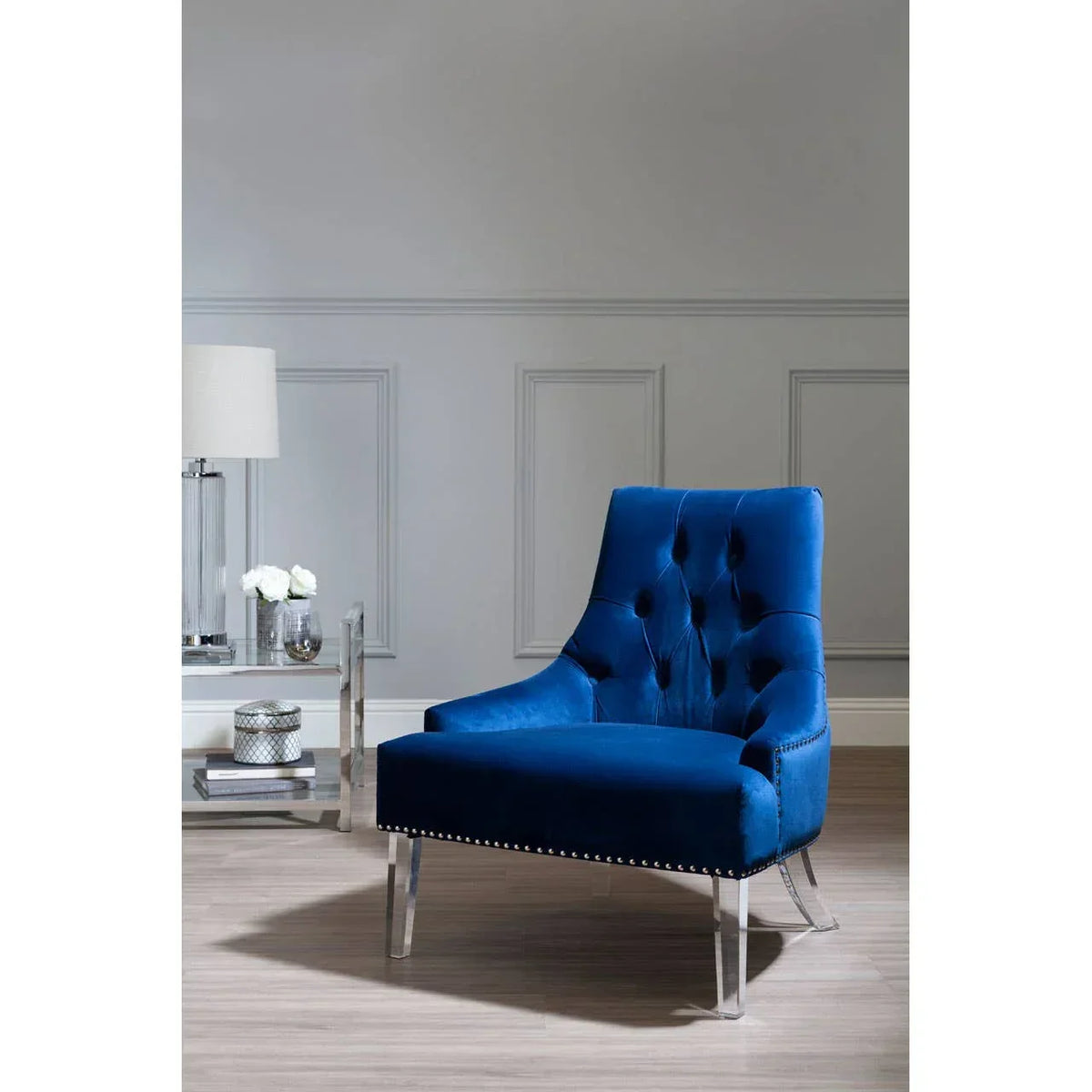 Blue velvet accent chair with clear acrylic legs in modern living room setting