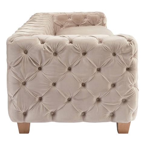 Beige velvet sofa with a tufted design, featuring a low back and armrests, supported by light wooden legs. The fabric has a soft, luxurious appearance, highlighting its elegant style suitable for home decor