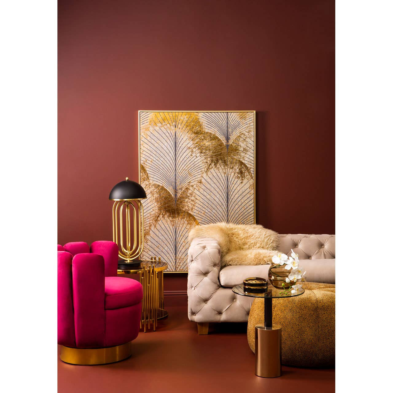 Beige velvet sofa with three seats, featuring tufted detailing and wooden legs, positioned in a stylish living room setting with a deep red wall, a large abstract artwork, a pink accent chair, and a gold side table