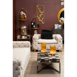 Beige velvet three-seat sofa with plush cushions, set against a deep maroon wall. A stylish coffee table with decorative items sits in front of the sofa, while a modern shelving unit displays various decor pieces in the background