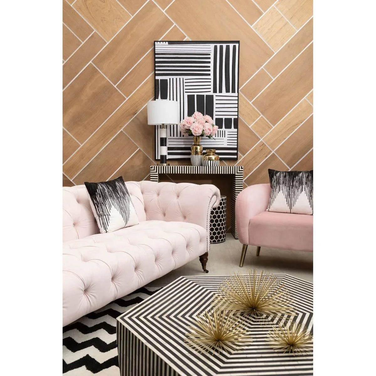 Blush pink tufted sofa set with black and white geometric cushions in a modern living room