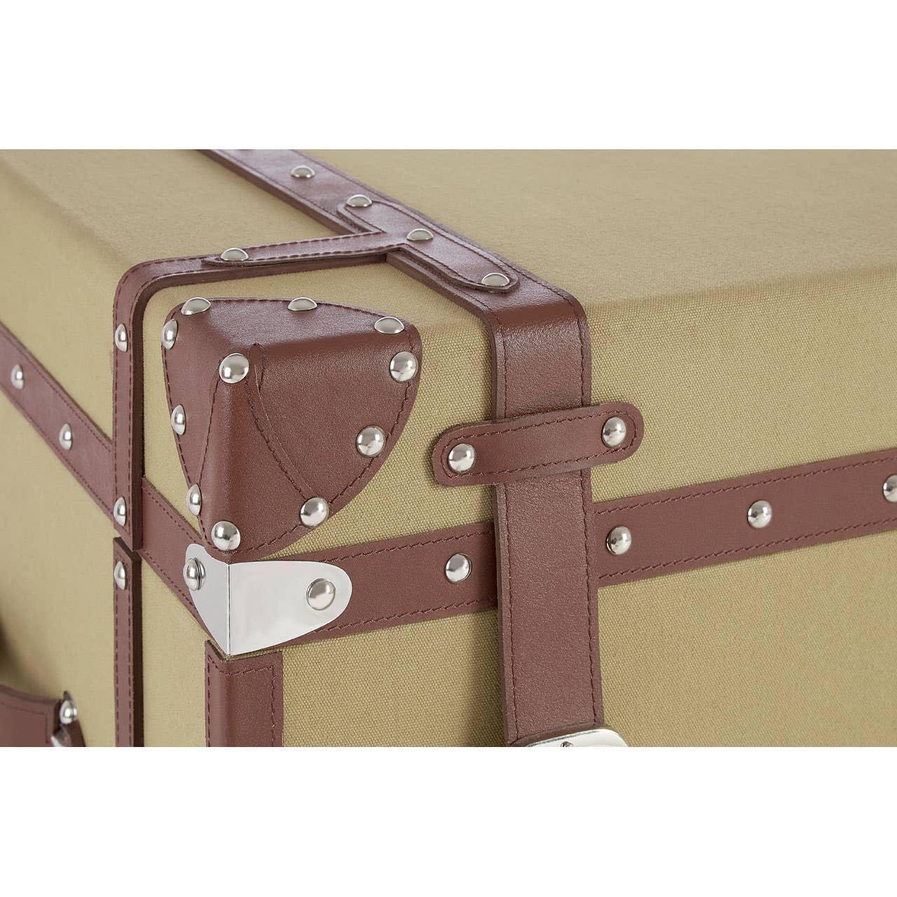 Beige storage trunk with brown faux leather straps and silver stud detailing, corner view