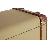 The Columbus Trunk Style Chest features a sleek, rectangular design with a smooth, golden surface and brown leather accents. The corners are reinforced with metal studs, and there are two drawers visible at the front, each with a simple handle. The overall aesthetic combines vintage charm with modern functionality