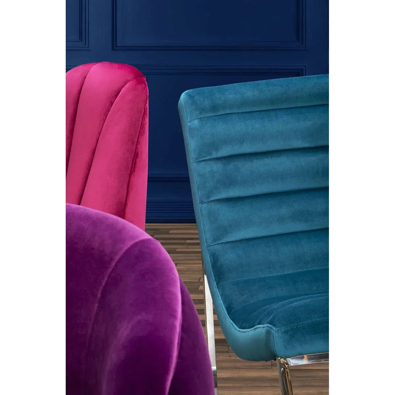 Blue velvet accent chair and pink velvet accent chairs with chrome legs on wooden floor