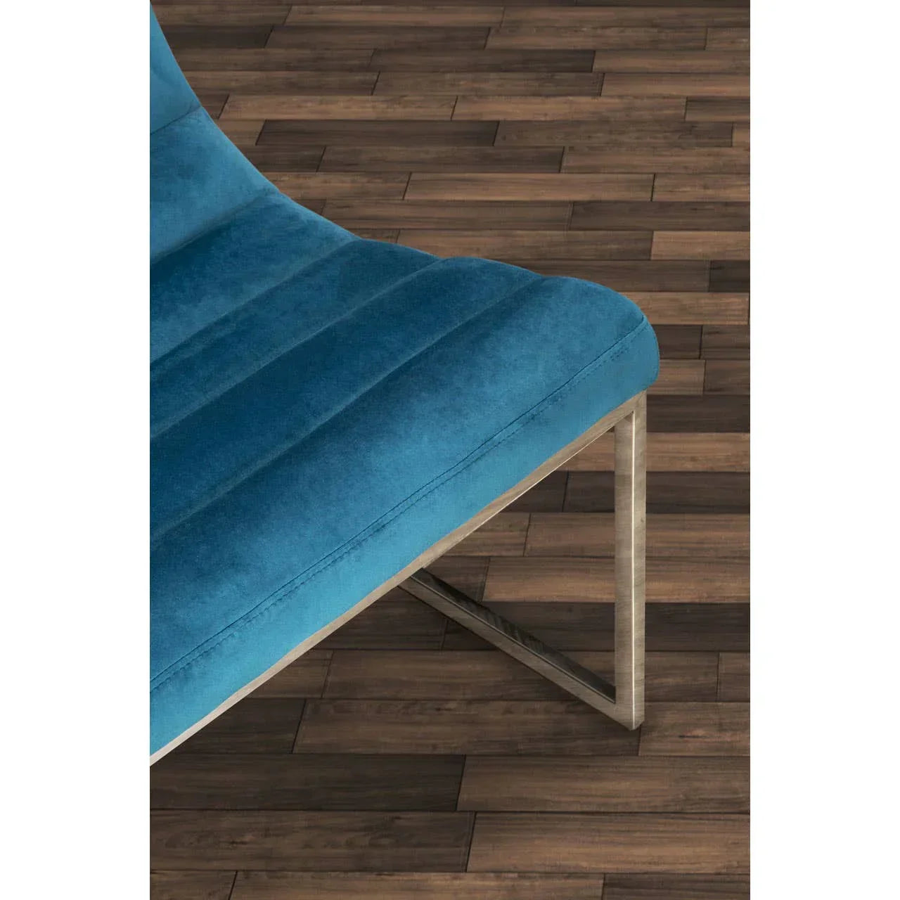 Blue velvet chair seat with metal legs on wood floor, close-up angle
