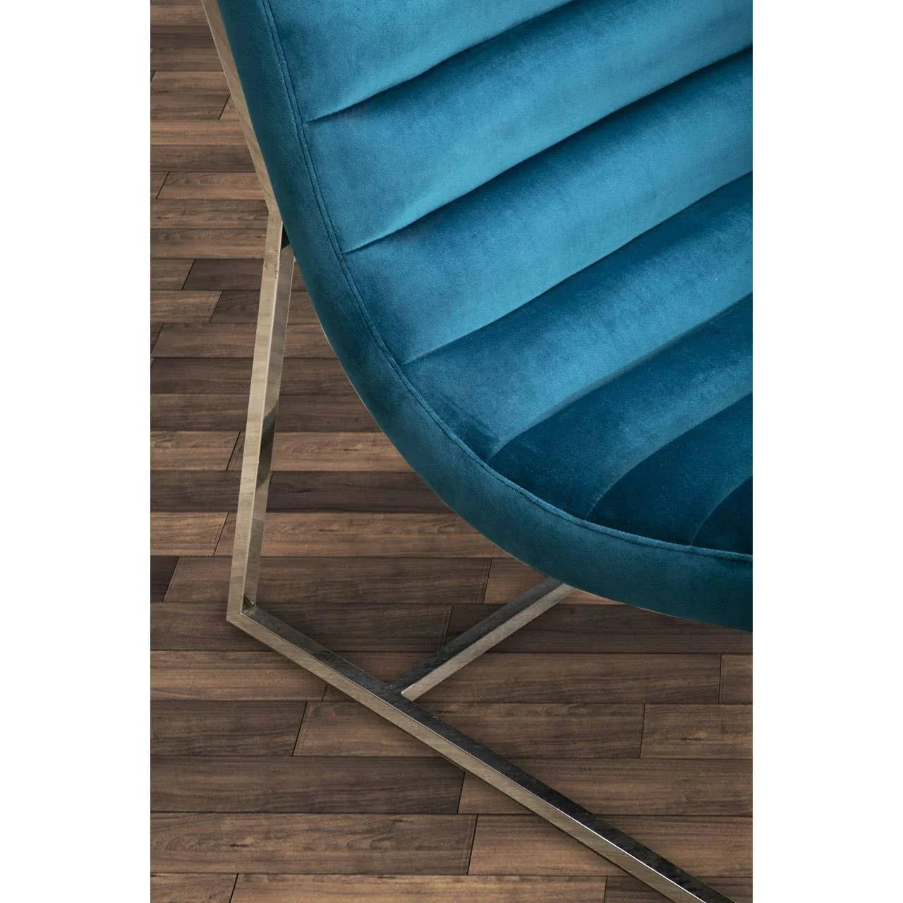 Blue velvet accent chair with metal base on wood floor, close-up of seat and frame