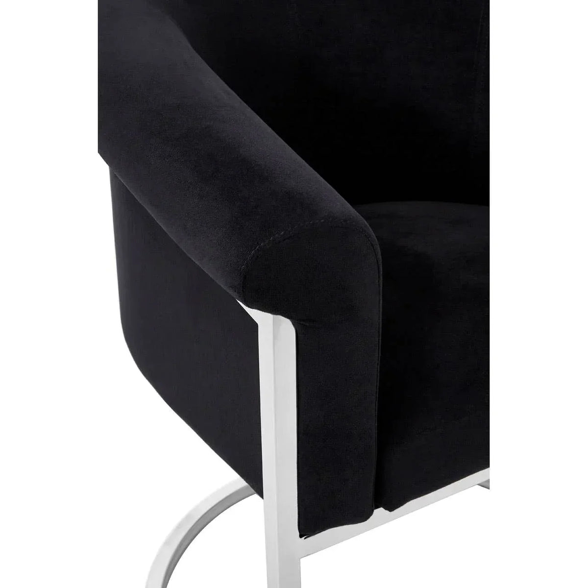 Black velvet upholstered armchair with chrome metal frame, close-up on arm and base