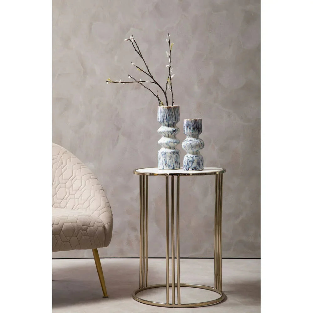 Gold metal side table with marble top, decorative blue vases and cream armchair beside