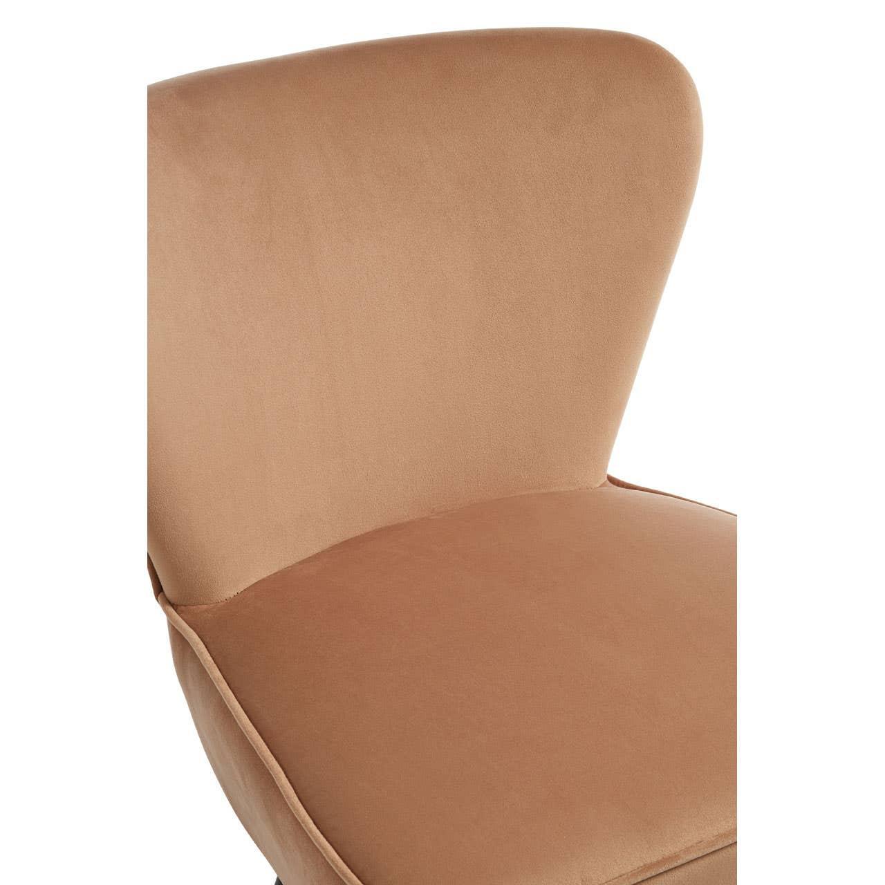 Close-up of tan velvet dining chair with curved backrest and padded seat
