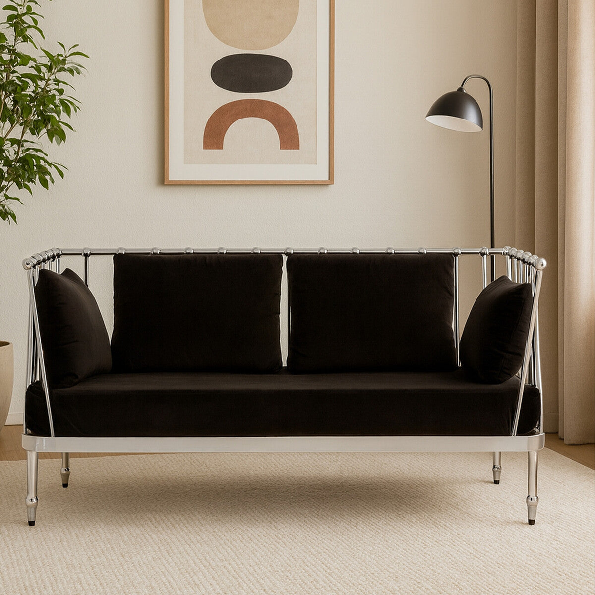A sleek two-seater sofa upholstered in black velvet, featuring a modern silver metal frame. The sofa has plush back cushions and is positioned in a stylish interior setting with a floor lamp and abstract wall art in the background. The flooring is light-colored, complementing the overall aesthetic