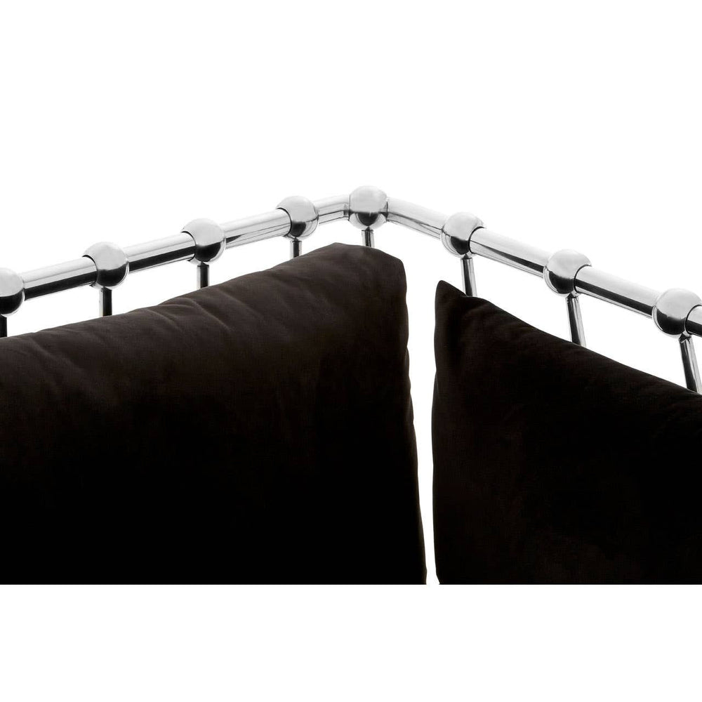 Black velvet upholstery covers the cushions of a three-seater sofa, featuring a sleek silver frame that outlines the backrest. The corner of the sofa shows a close-up of the frame's detailing, highlighting the elegant design and plush texture of the fabric