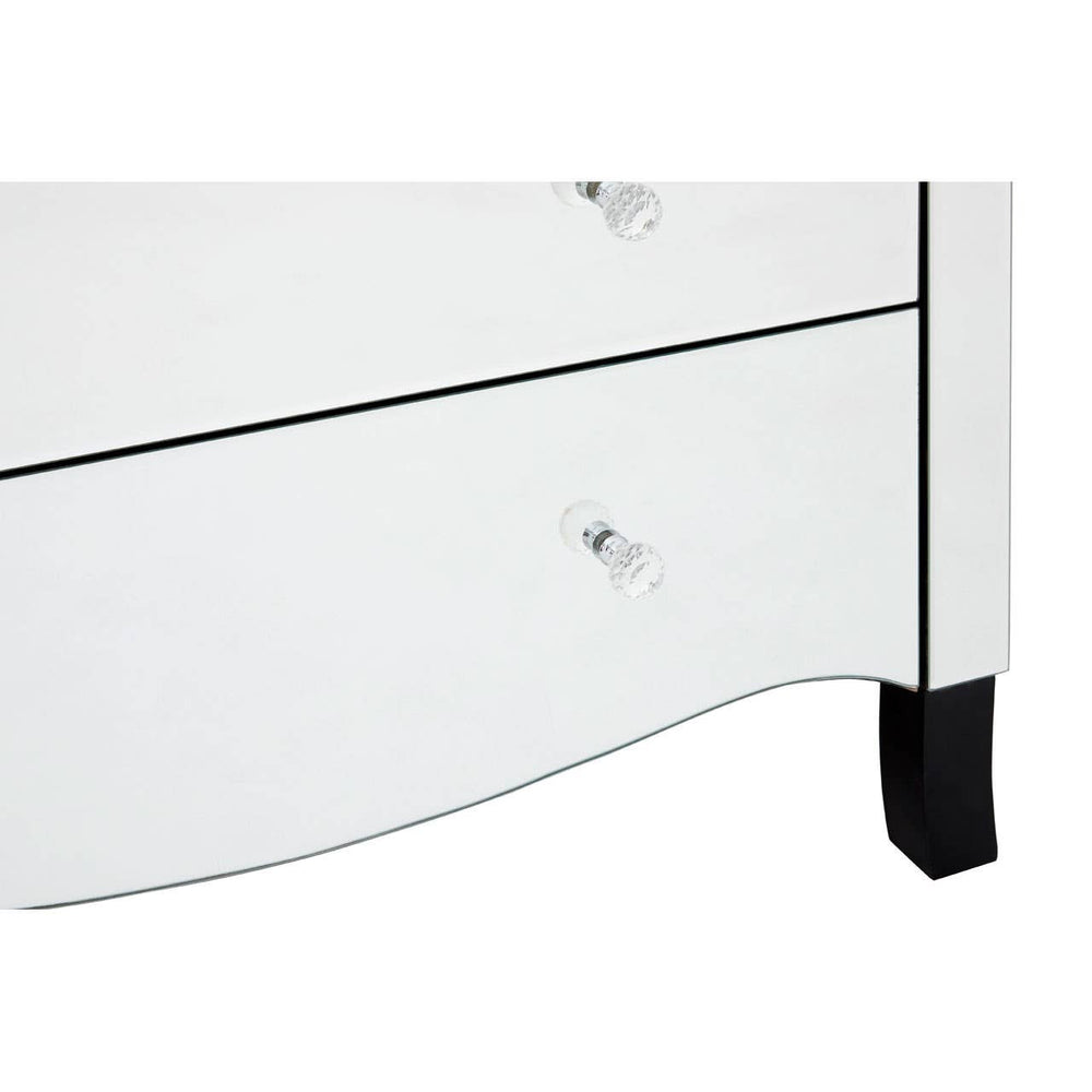 White chest of four drawers featuring a sleek design with a curved front and black feet. Each drawer has a clear crystal knob for easy opening. The surface is smooth and glossy, reflecting light
