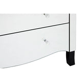 White chest of four drawers featuring a sleek design with a curved front and black feet. Each drawer has a clear crystal knob for easy opening. The surface is smooth and glossy, reflecting light