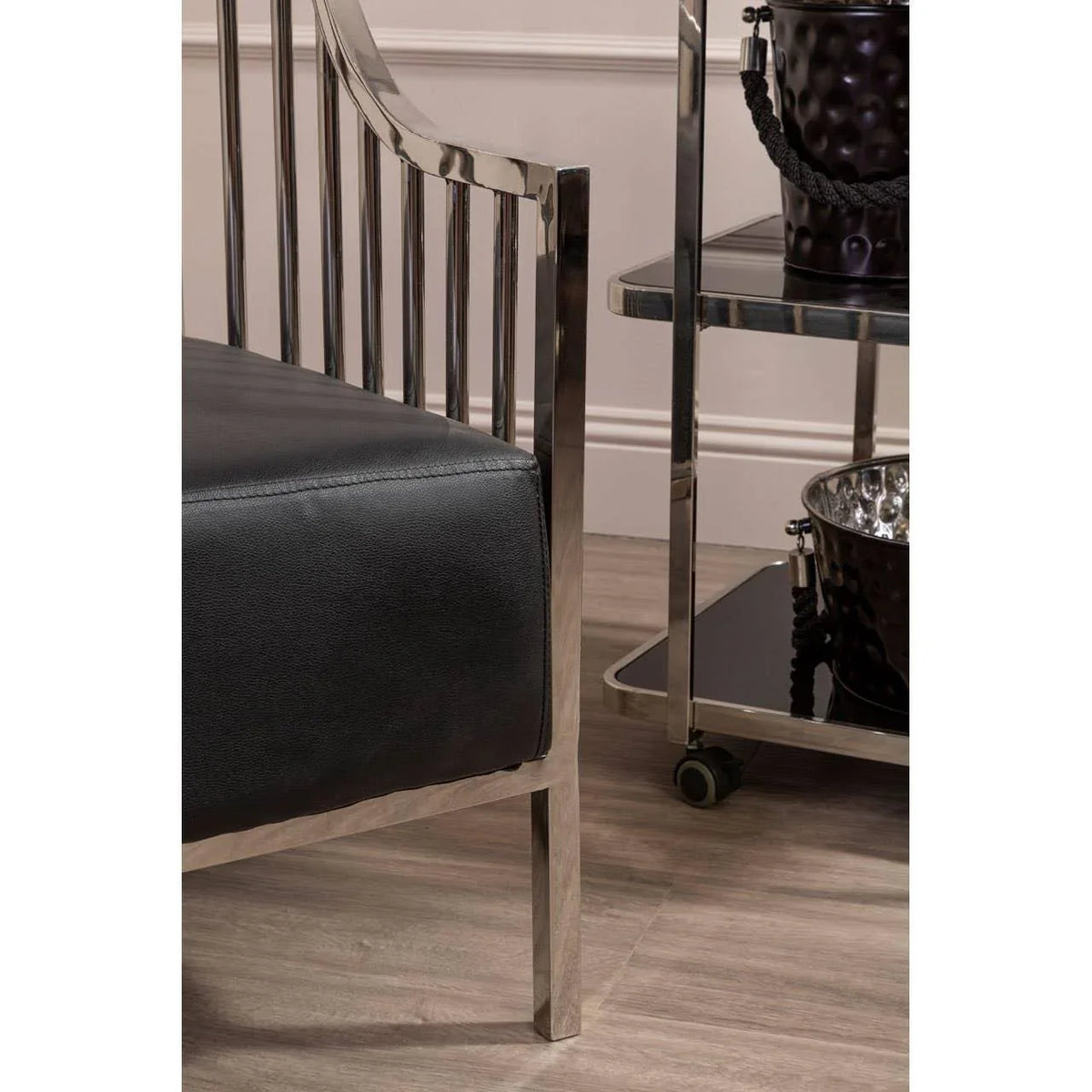 Silver metal and black leather chair corner beside chrome drinks trolley on wood floor