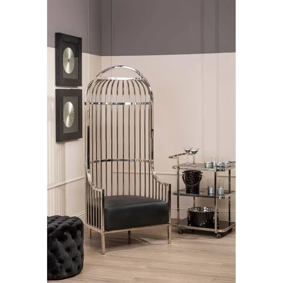 Modern chrome accent chair with black cushioned seat beside glass bar cart in living room