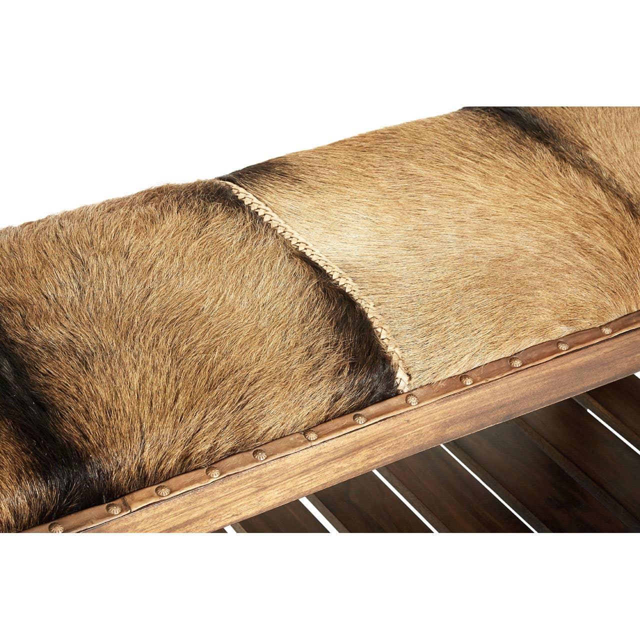 Brown cowhide bench seat with wooden frame and decorative metal studs, close-up view