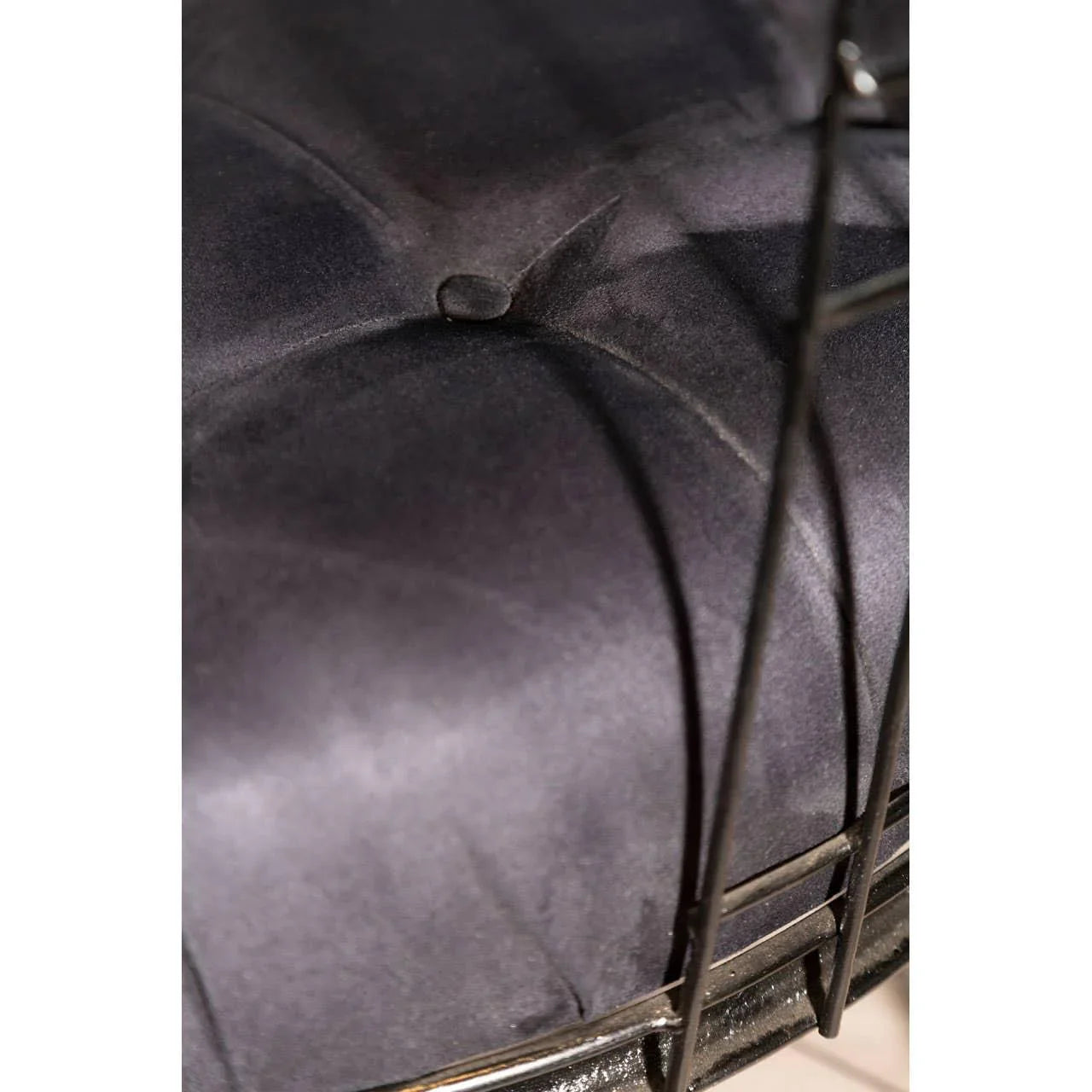 Closeup of black velvet dining chair seat cushion with button tufting and metal frame
