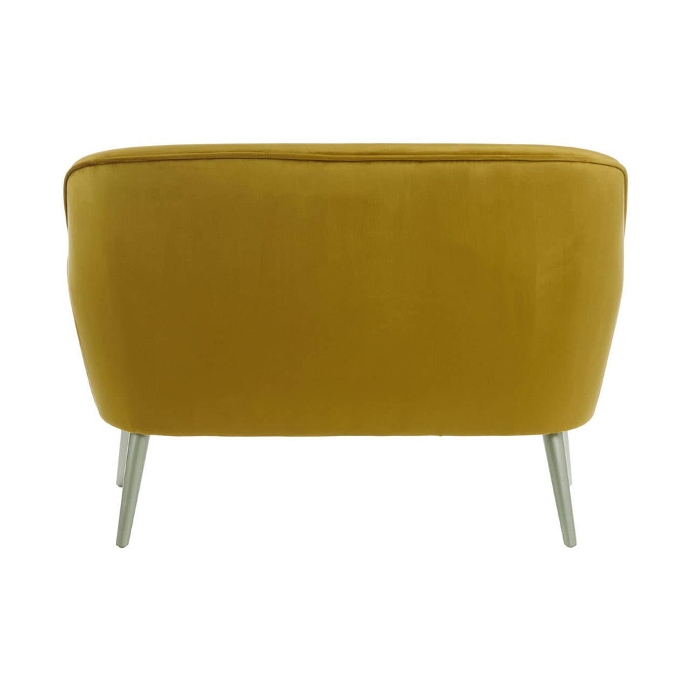 Mustard yellow velvet two-seater sofa with a rounded backrest and sleek metal legs. The upholstery has a soft texture, and the overall design is modern and minimalist